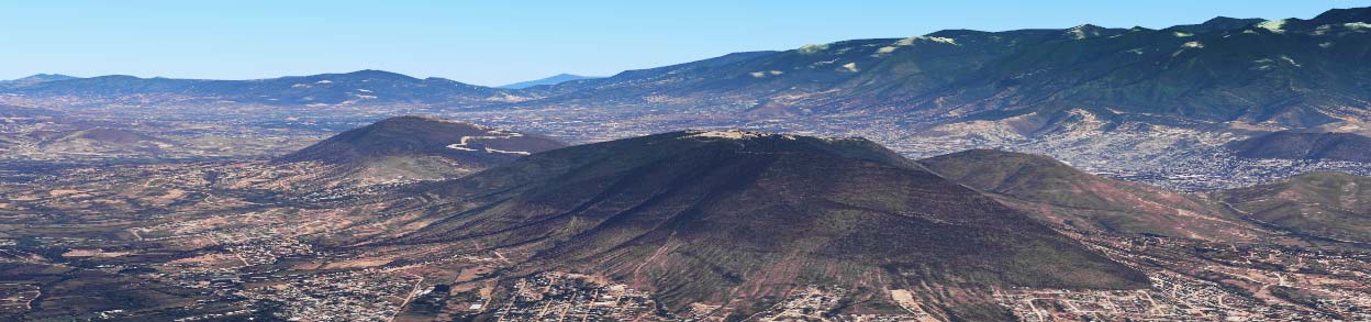 The sandy stonework of Monte Alban is just about visible on top of the craggy hill, centre shot