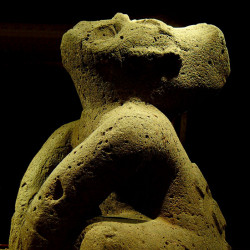 An Olmec statue of a person sitting with an upturned face